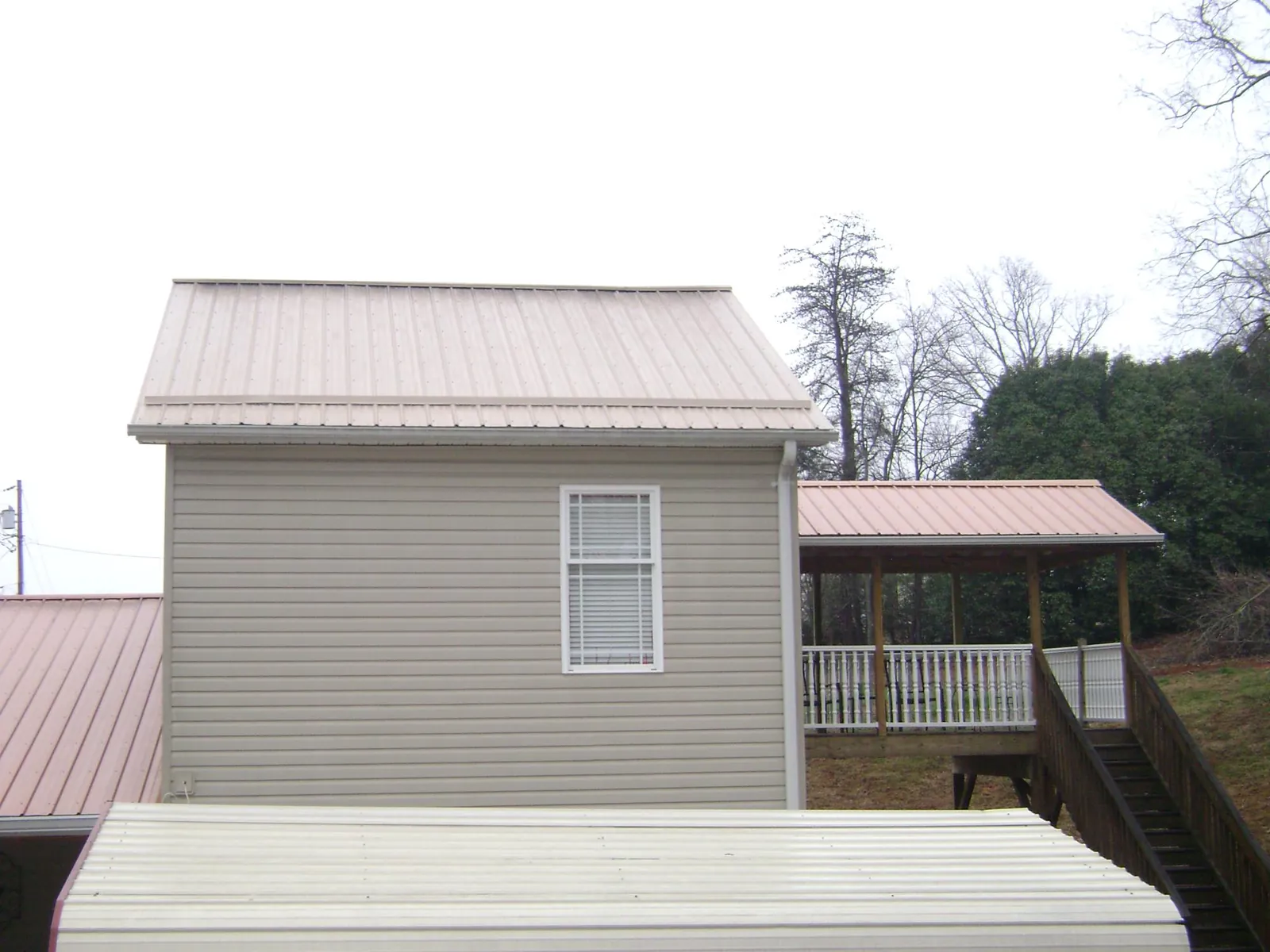 Tan metal roofs on a two story addition and attached porch, from a Roof Replacement job in Reedsville